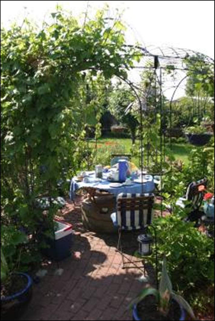 Sitzgruppe mit Tisch aus Eukalyptusholz im Rosenpavillon